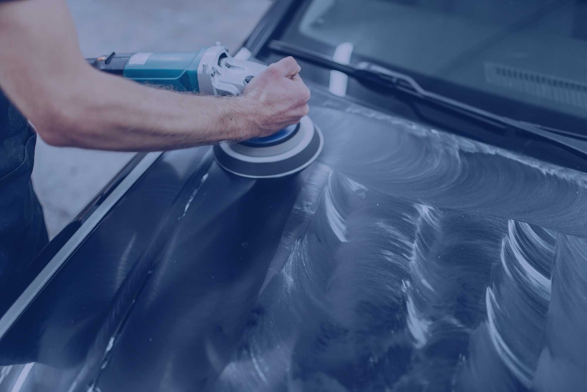 Male person with polishing machine cleans car hood